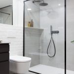 UN BAÑO DE DISEÑO MODERNO CON DUCHA EN BLANCO Y NEGRO